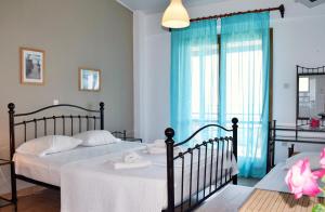 een slaapkamer met 2 bedden en een raam met blauwe gordijnen bij Ostria's House in Ratzaklíon