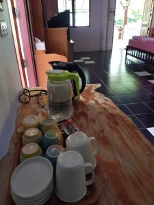 een tafel met kopjes en een koffiezetapparaat. bij Ban Sabai Sabai Guest House in Kanchanaburi