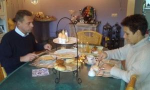 Dwóch mężczyzn siedzących przy stole jedzących jedzenie w obiekcie Bed en Breakfast en Bike w mieście Sommelsdijk