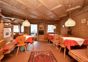 a restaurant with wooden ceilings and tables and chairs at Post Hotel Moena in Moena