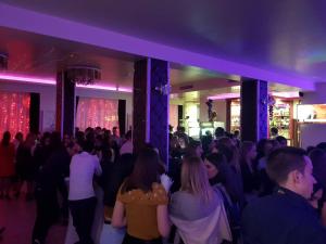a crowd of people dancing in a room with purple lighting at Hotel Aris in Sofia