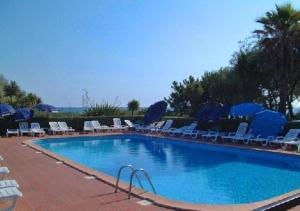 una grande piscina con sedie e ombrelloni blu di Résidence les Marines de Moriani Emeraude Locations a Moriani-Plage