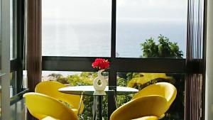 a table and yellow chairs in front of a window at Apartamento Doreen in Caniço