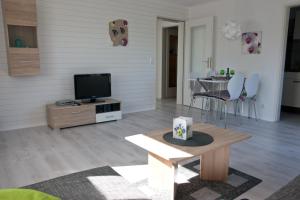 a living room with a tv and a table at Appartmenthaus Kehrwieder in Sankt Peter-Ording
