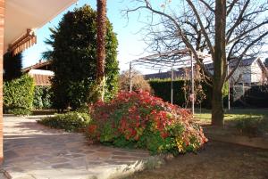 un jardín con flores rojas y cenador en La Cascina, en Agliè