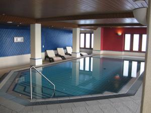 una gran piscina con sillas en un edificio en Hotel Hubertus, en Obergesteln