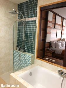 a bathroom with a bath tub and a mirror at Taman Resort in Phitsanulok