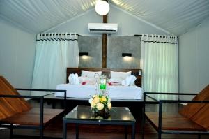 a bedroom with a bed and a table with flowers on it at Kottawatta Village in Udawalawe
