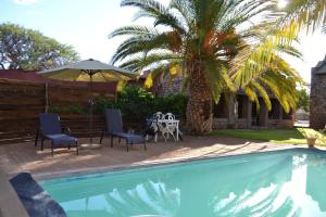 a pool with a table and chairs and a palm tree at Savanna Guest Farm in Grünau