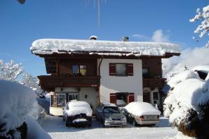 a snow covered house with cars parked in front of it at Landhaus Bachler in Brixen im Thale