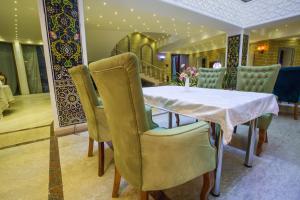 a dining room with a white table and chairs at Karvon-Saroy Hotel in Andijan