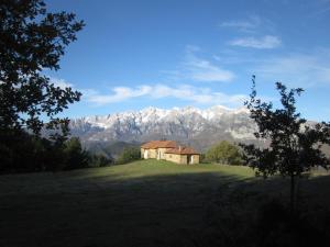 una casa su un campo con montagne sullo sfondo di Posada Torcaz a Cahecho