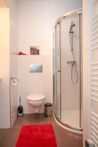 uma casa de banho com um chuveiro, um WC e um tapete vermelho em Stylish apartment a few steps from metro em Praga