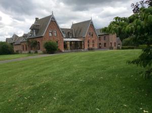 a large brick building with a large grass field at Haras de Baudemont in Ittre