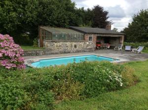 a swimming pool in front of a stone house at Haras de Baudemont in Ittre