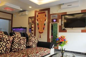 a living room with a couch and a tv at Sri Sarvesha Residency Temple view in Tiruvannāmalai