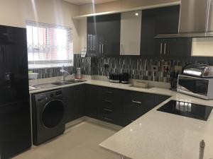 a kitchen with black cabinets and a sink and a dishwasher at AYA LUXURY APARTMENTS 79 in Durban
