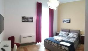 a bedroom with a bed and a window with red curtains at B&B la cascata in Bolognano