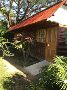 a house with a wooden door and a tree at Hotel Cabanas La Teca in Liberia