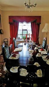 un comedor con una mesa larga y cortinas rojas en Charlotte's Way B&B, en Banagher