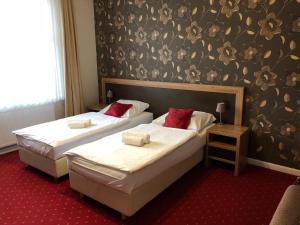 two beds in a hotel room with white sheets and red pillows at Villa Zagórze in Rumia