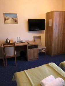 a hotel room with a desk and a tv and a bedroom at Villa Zagórze in Rumia