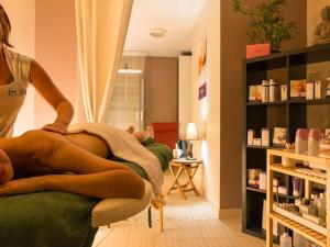 a woman is sitting on a bed in a room at Les Sables du Midi in Valras-Plage