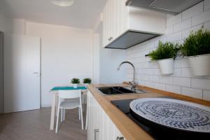 Appartamento Indaco by un Mare di Blu في ماكاري: مطبخ مع حوض وطاولة مع نباتات الفخار