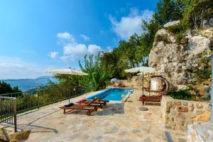 uma piscina com cadeiras e guarda-sóis ao lado de uma montanha em Villa Stone-Exceptional private Estate em Mlini