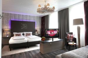 a bedroom with a bed and a tv in it at Hotel am Markt Bacharach in Bacharach