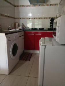 uma cozinha com uma máquina de lavar roupa e armários vermelhos em Les Jardins Créoles em Cilaos