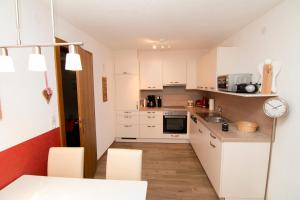 a kitchen with white cabinets and a table and chairs at Ferienwohnung Kreidl in Schlitters