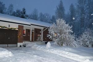 a house is covered in snow in front of it at House Olkka by the river in Rovaniemi