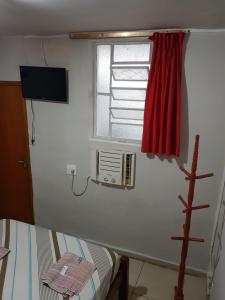a room with a window with a heater and a red curtain at Hotel Cabo Finisterra in Rio de Janeiro