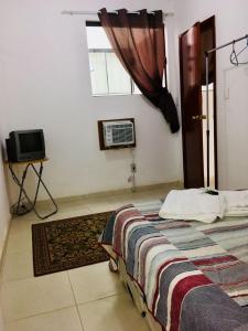 a bedroom with a bed and a window and a television at Resende Flats GR in Resende