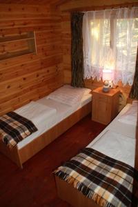 a bedroom with two beds in a log cabin at Ośrodek Portus in Międzywodzie