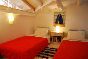 2 Betten in einem kleinen Zimmer mit roter Bettwäsche in der Unterkunft Skiathos Driades in Koukounaries