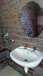 un bagno con lavandino e specchio su un muro di mattoni di Kitolie Home and Lodge a Moshi