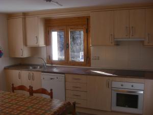 a kitchen with wooden cabinets and a table and a window at Vivienda Lanzón in Salinas de Bielsa