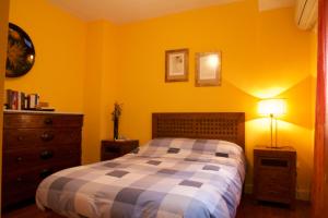 塞维利亚Apartamento San Benito C的卧室拥有黄色的墙壁,配有一张床和梳妆台