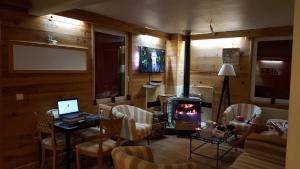 a living room with a stove and a table with a laptop at Le reposoir in Mont-Saxonnex