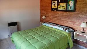 um quarto com uma cama verde e uma parede de tijolos em Cabañas Pampa em Mina Clavero