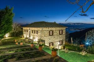 una casa de piedra con luces en el patio por la noche en Iliopetra Suites en Agios Lavredios