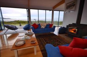 a living room with a blue couch and a fireplace at Mures Cloudy Bay Retreat in South Bruny
