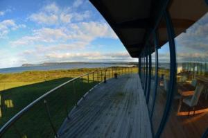 a balcony of a house with a view of the ocean at Mures Cloudy Bay Retreat in South Bruny