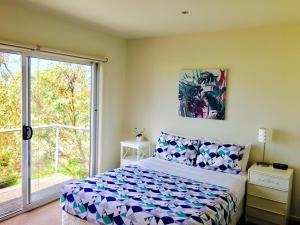 a bedroom with a bed and a large window at Seaside Pleasure in Apollo Bay