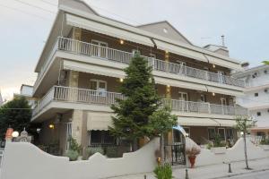 un gran edificio con un árbol delante en Villa Elena, en Olympiakí Aktí