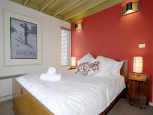 a bedroom with a white bed with a red wall at Twirligig in Mount Hotham