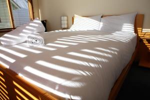 a bed with a white comforter with the sun shining on it at Cobungra in Mount Hotham