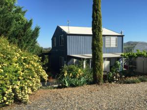 a black house with trees and flowers at Cottage in the Country in Tumut